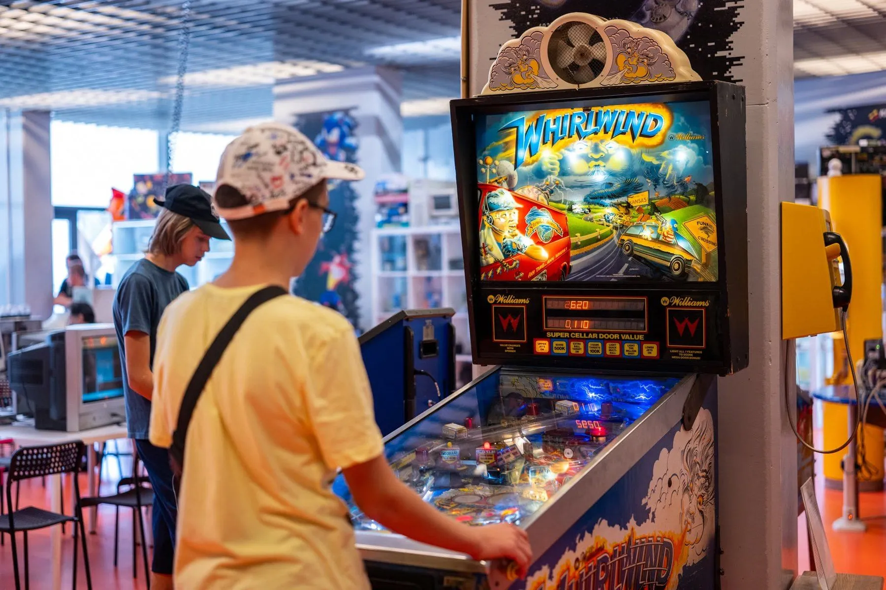 Zwiedzający grają na pinballu Whirlwind w Muzeum gier i technologii